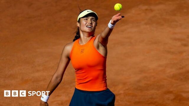 Emma Raducanu serves on a clay court