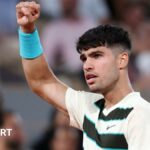 Carlos Alcaraz raises his right arm