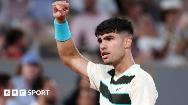 Carlos Alcaraz raises his right arm