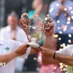 Lloyd Glasspool and Julian Cash hold the men's doubles trophy at Queen's