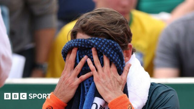 Alex de Minaur covers his face with a towel at the French Open