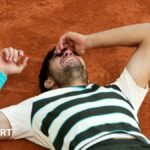 Carlos Alcaraz lies on the court after defending his French Open title
