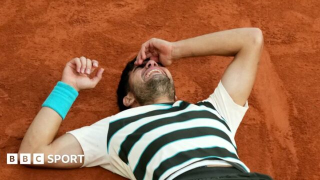 Carlos Alcaraz lies on the court after defending his French Open title