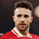 Diogo Dalot carries some flowers as he lays a Manchester United tribute to Diogo Jota and Andre Silva at Anfield