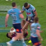 Na obrázku: Hamiso Tabuai-Fidown (drží loptu) pravou nohou, zatiaľ čo sa snaží dostať na nohy a hviezdu NSW Latrell Mitchell's Groin
