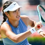Emma Raducanu holds up a tennis racquet