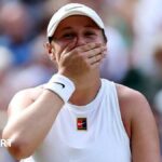 Amanda Anisimova covers her mouth with her hand