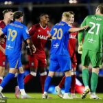 Šokujúci okamih futbalového hráča, ktorý sa snaží bojovať proti opozičným hráčom počas úvodnej hry sezóny - predtým, ako je bezpečnosť plochá