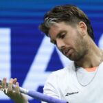 Cameron Norrie looks at his racquet during a 2025 US Open defeat by Novak Djokovic