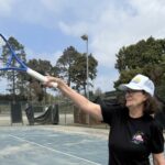 Tennis Great Pam Shriver ukazuje jej raketou, keď stála na ihrisku poškodenou v paľbe Palisades.