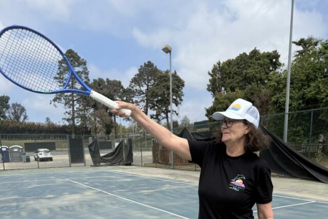 Tennis Great Pam Shriver ukazuje jej raketou, keď stála na ihrisku poškodenou v paľbe Palisades.