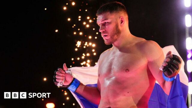 Vadim Nemkov enters the cage wrapped in a Russian flag