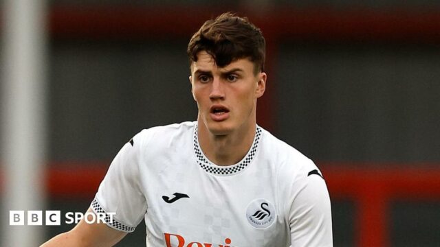 Joel Cotterill standing with the ball at his feet and his right arm held out during a pre-season match for Swansea