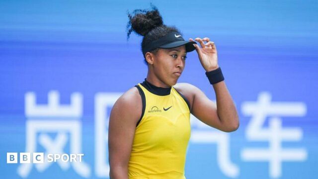 Naomi Osaka looking glum with her hand on her hat