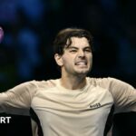 Taylor Fritz raises his arms in celebration after beating Lorenzo Musetti at the ATP Finals