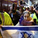 Policajti odprevadia ženu s izraelskou vlajkou preč od propalestínskych demonštrantov pred Villa Park