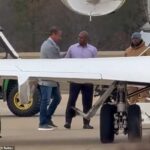 Lane Kiffin (vľavo) bol videný opúšťať SUV so šoférom a kráčať po asfaltovej ploche k svojmu čakajúcemu lietadlu, zatiaľ čo stovky jeho bývalých priaznivcov ponúkali zborové bučanie a nadávky.