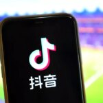 Logo TikTok na mobilnom telefóne na futbalovom štadióne