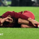 An unidentified player clutches his ankle and covers his face