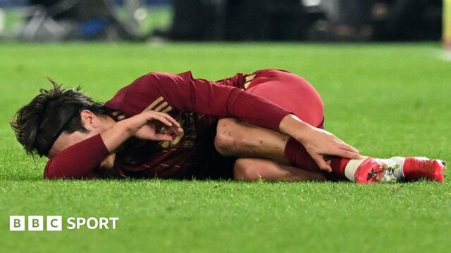 An unidentified player clutches his ankle and covers his face