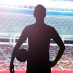 Silueta futbalového hráča stojaceho na štadióne s loptou