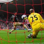 Darren Bent zo Sunderlandu počas zápasu Barclays Premier League medzi Sunderlandom a Liverpoolom sleduje, ako jeho strela smeruje medzi Glena Johnsona a Pepeho Reinu z Liverpoolu a do bránky.