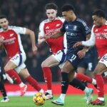 Ollie Watkins z Aston Villy beží s loptou, zatiaľ čo je pod tlakom Declana Ricea a Jurriena Timbera z Arsenalu.