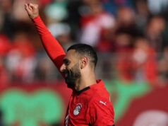 Salah trest posiela 10-mužov Egypt cez Afcon Mohamed Salah v červenom egyptskom drese, bielych trenírkach a čiernych štulpniach strieľa ľavou nohou a strieľa pokutový kop proti Juhoafrickej republike na Afcon 2025. Lopta je vidieť nízko na obrázku úplne vpravo a smeruje k bráne, ktorú nie je vidieť. Mierne rozmazané pozadie sú dvaja hráči Egypta a traja hráči Juhoafrickej republiky v zelenom a žltom, ktorí sa práve začínajú presúvať do pokutového územia po tom, čo čakali na okraji 18-yardového poľa.