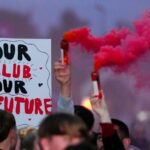 Znak hovorí "Náš klub naša budúcnosť" je držaný vo vzduchu počas protestu Salford Red Devils v roku 2025