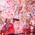 Kim Little a Leah Williamsonová z Arsenalu zdvihli nad hlavu trofej ženskej Ligy majstrov UEFA počas osláv trofeje na Emirates Stadium.