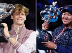 Čo je to Million Dollar One Point Slam? Naomi Osaka je držiteľkou trofeje Australian Open v roku 2021. Oblečenú má modrošedú teplákovú bundu s ružovým zipsom, na hlave má modrý šilt a široko sa usmieva.