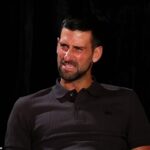 Novak Djokovič robí grimasy, keď sa ho pýtajú, koľko Austrálčanov by dovolilo svojmu psovi olízať si zmrzlinu na edícii Nine's Australian Open The Hundred s Andym Leem.