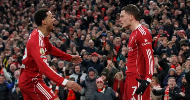 Správy z Liverpoolu: Hugo Ekitike priznáva problémy s Reds, zatiaľ Dvaja futbalisti v červených uniformách oslavujú gól pred nadšeným publikom, pričom niekoľko fanúšikov v pozadí má na sebe červené šatky.