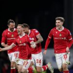 Hráči Wrexhamu oslavujú po tom, čo tímový kolega Arthur Okonkwo (bez obrázku) zachránil piatu penaltu od Omariho Hutchinsona