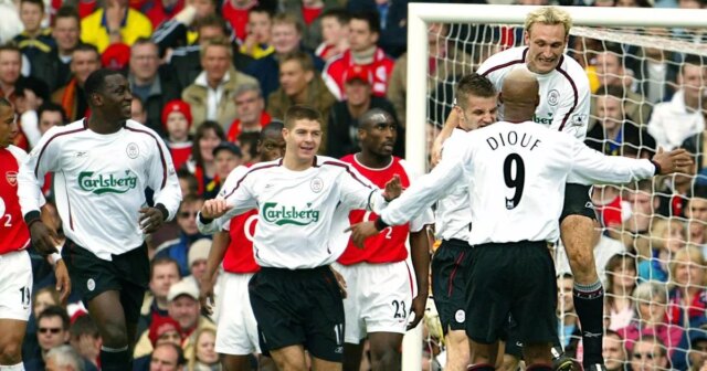 Skupina futbalistov v bielo-červených uniformách oslavuje pred bránkou počas zápasu s veľkým davom divákov v pozadí.