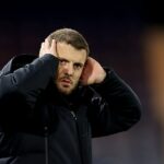 Manažéra Luton Town Jacka Wilshera museli obmedzovať jeho vlastní hráči uprostred zúrivej konfrontácie s fanúšikom.