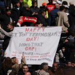 Fanúšikovia Arsenalu držia pred fanúšikmi Tottenhamu transparent s nápisom Happy St. Totteringham's Day