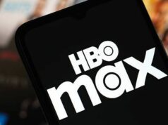 Ako sledovať TNT Sports na HBO Max, pretože pokrytie discovery+ zmizne Detailný pohľad na smartfón s logom HBO Max na obrazovke. Pozadie je rozmazané a zobrazuje rôzne zábavné médiá v okolí.