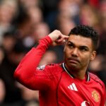 Casemiro oslavuje strelenie gólu pre Manchester United tým, že ukazuje svoj pravý ukazovák na stranu čela s prísnym výrazom na tvári.