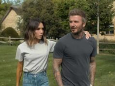 David Beckham spôsobil spor so susedmi o premenu domu v Cotswolds v hodnote 6 miliónov libier Jednotlivec v sivom tričku a khaki nohaviciach stojí vo vonkajšom prostredí v sprievode osoby v bielom tričku a modrých džínsoch. Na pozadí je dom a svieža zelená krajina.