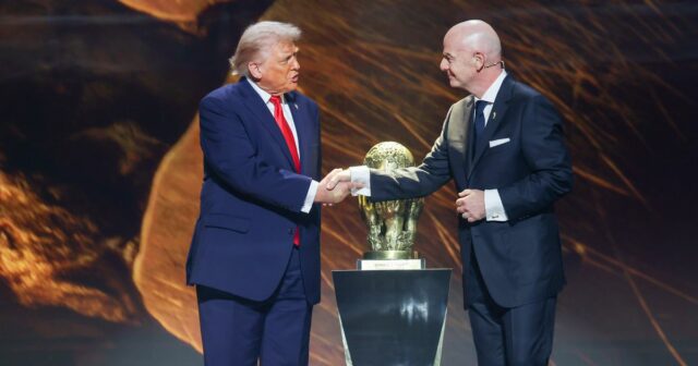 Jednotlivec v spoločenskom oblečení, stojaci na tmavom pozadí a v ruke drží zlatú trofej.