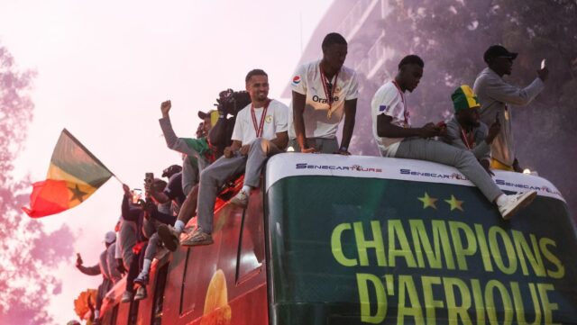 Senegalský národný tím šampiónov AFCON 2025 pozdravuje fanúšikov z tímového autobusu počas víťazných osláv v uliciach