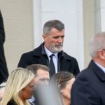 Skupina jednotlivcov oblečených v slávnostnom oblečení, pozostávajúcom z oblekov a kravat, spolu stojí a pozorne sleduje udalosť alebo prezentáciu, ktorá sa pred nimi odohráva. Jednotlivci sa zhromažďujú vo vnútornom prostredí, možno na formálnom stretnutí alebo ceremónii.