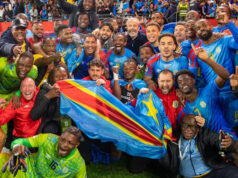 „Toto je väčšie ako futbal“ – DR Kongo sa uchádzalo o ukončenie 52-ročného čakania na majstrovstvá sveta Zložený obrázok pozostávajúci z dvoch vertikálnych obrázkov, pričom ľavý zobrazuje bývalého prezidenta Konga v Kongu Mobutu Sese Seka a pravá strana zobrazuje troch vojakov v maskáčoch so zbraňami. Mobutu kráča po červenom koberci, má na sebe pevne zapnutý sivý oblek, okuliare, klobúk z leopardej kože a vo zvislej polohe drží ozdobne vyrezávanú palicu. Môžu ho obklopovať ďalší muži v oblekoch, ako aj jeden muž v oficiálnom vojenskom oblečení. Všetci mlado vyzerajúci vojaci majú na sebe nepriestrelné vesty. Jeden nosí zelenú baretku, ďalší prilbu a tretí čiapku. Stoja pred obrneným vozidlom