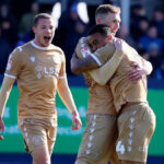 Šéf Bromley Andy Woodman dvíha trofej víťazov z finále postupu do Národnej ligy obklopený hráčmi Bromley v stánku na štadióne Wembley.
