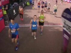 Bývalá hviezda Arsenalu Aaron Ramsey zabehol neuveriteľný čas londýnskeho maratónu len niekoľko týždňov po odchode do dôchodku Traja bežci sa zúčastňujú maratónu na vydláždenej mestskej ulici s červenou stenou a reklamami v pozadí. Prítomní sú diváci a bežci sú oblečení v atletickom oblečení so zameraním na preteky.