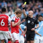 Rozhodca Anthony Taylor ukazuje žltú kartu Erlingovi Haalandovi a Gabrielovi počas zápasu Premier League medzi Manchestrom City a Arsenalom na Etihad Stadium.