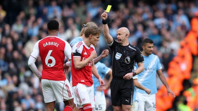 Rozhodca Anthony Taylor ukazuje žltú kartu Erlingovi Haalandovi a Gabrielovi počas zápasu Premier League medzi Manchestrom City a Arsenalom na Etihad Stadium. 