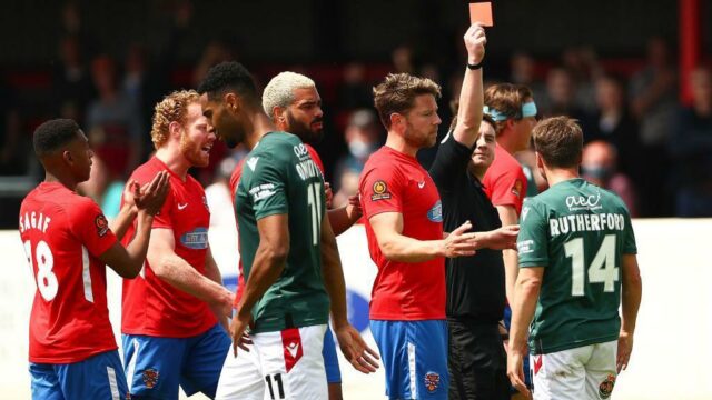 Paul Rutherford z Wrexhamu sa postaví proti Angelovi Balantovi z Dagenhamu a Redbridge počas zápasu Dagenham & Redbridge vs Wrexham v roku 2019