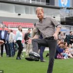 Princ Harry sa v stredu ráno postavil do centra pozornosti, keď navštívil tím Western Bulldogs AFL a vyskúšal si kopačky s hviezdami Tomom Liberatorem (vľavo) a Adamom Treloarom.